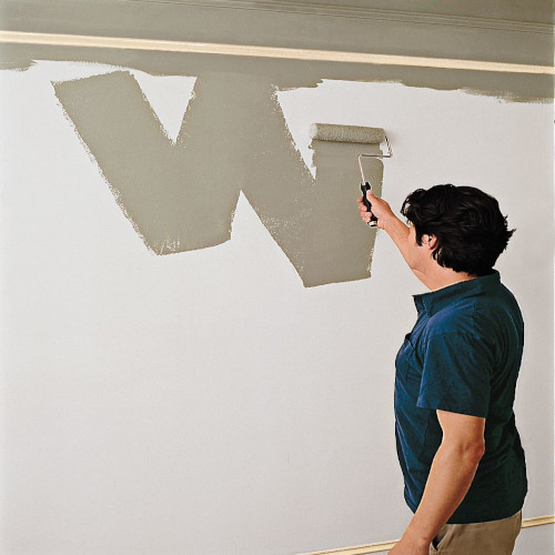 A man painting a wall in a w pattern, starting from the top