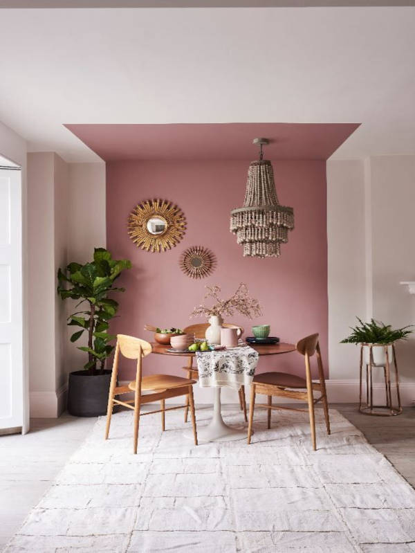 A section of a large while wall that has been painted pink in order to zone that area into a dining area.